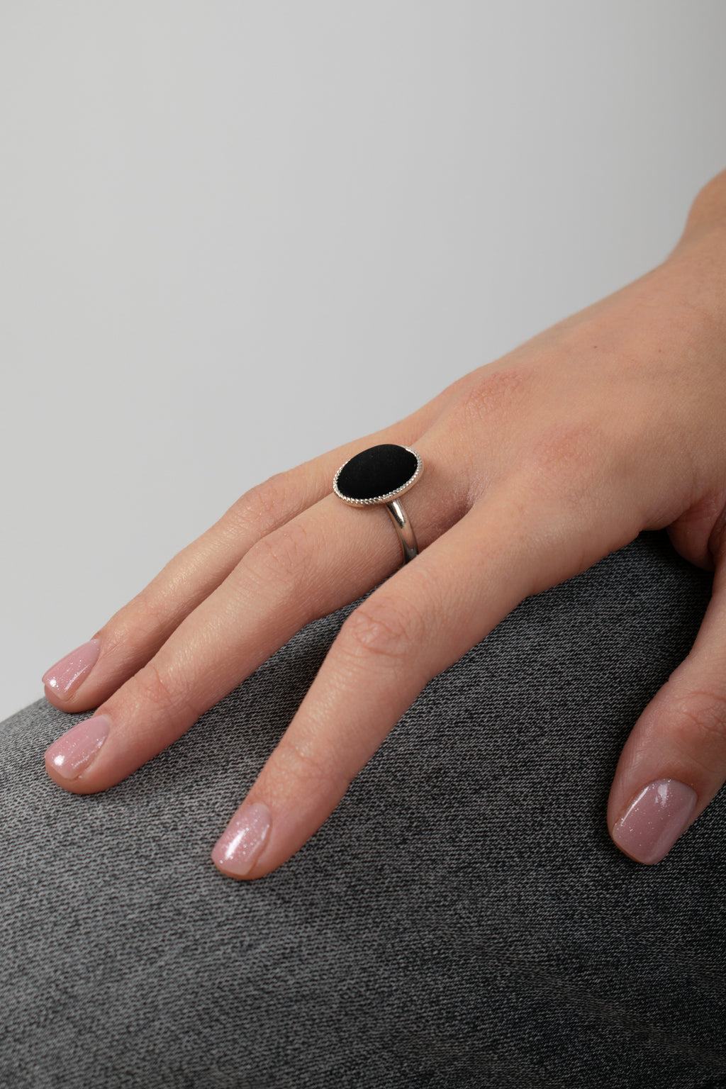 Anello cabochon nero regolabile indossato - dettaglio pietra ovale e base metallo anallergico