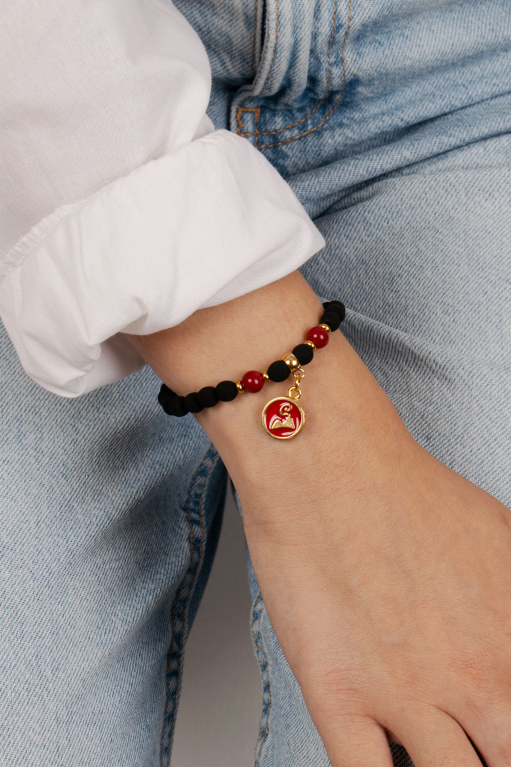 Donna indossa bracciale con perline nere e rosse e ciondolo double face San Gennaro e Vesuvio con finitura dorata