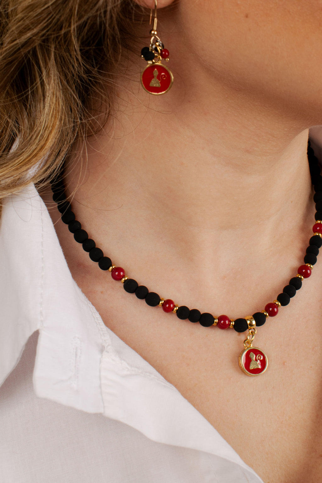 Donna indossa bracciale con perline nere e rosse e ciondolo double face San Gennaro e Vesuvio con finitura dorata