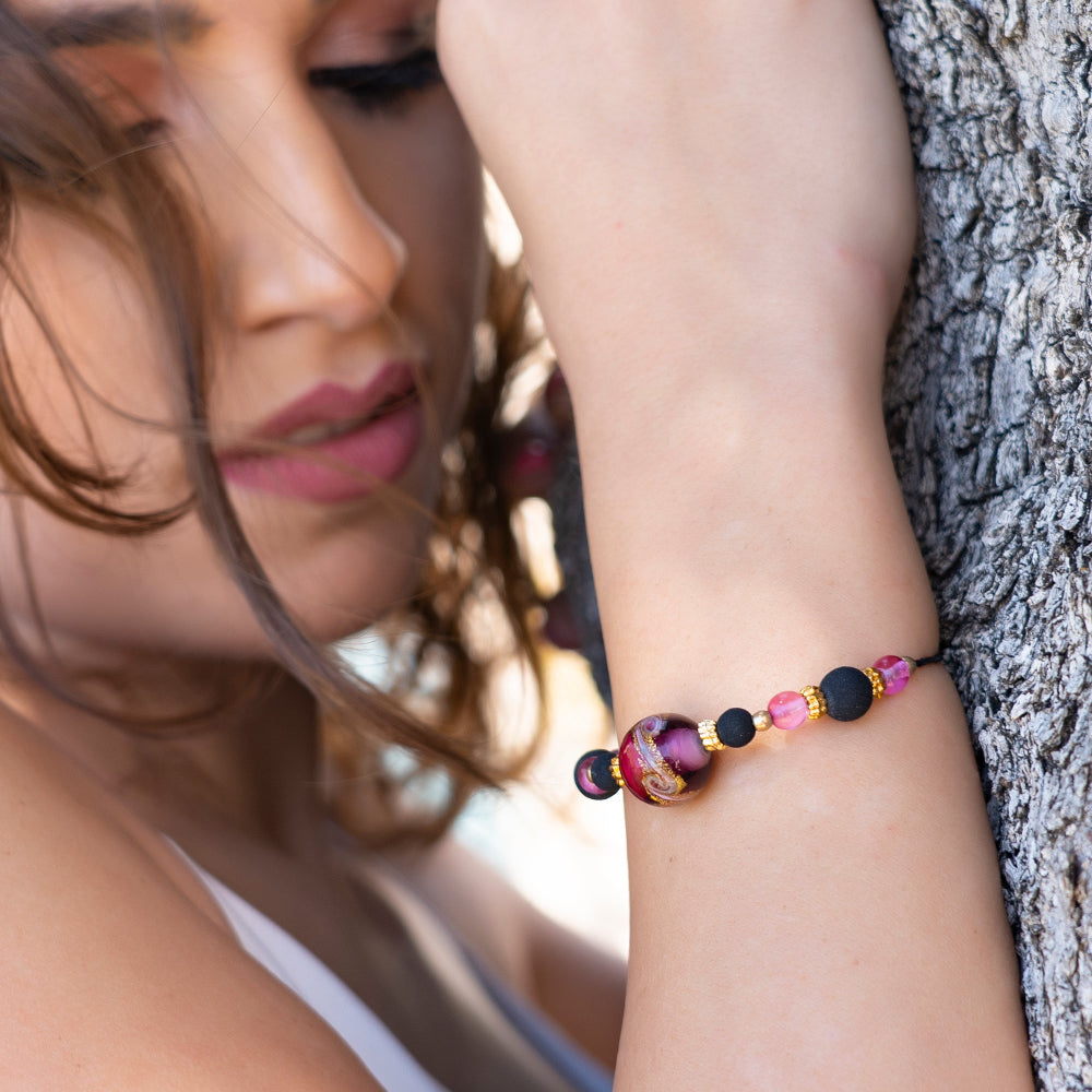 Modella indossa bracciale con perla centrale in vetro di Murano rosa e dettagli in metallo dorato Giamas