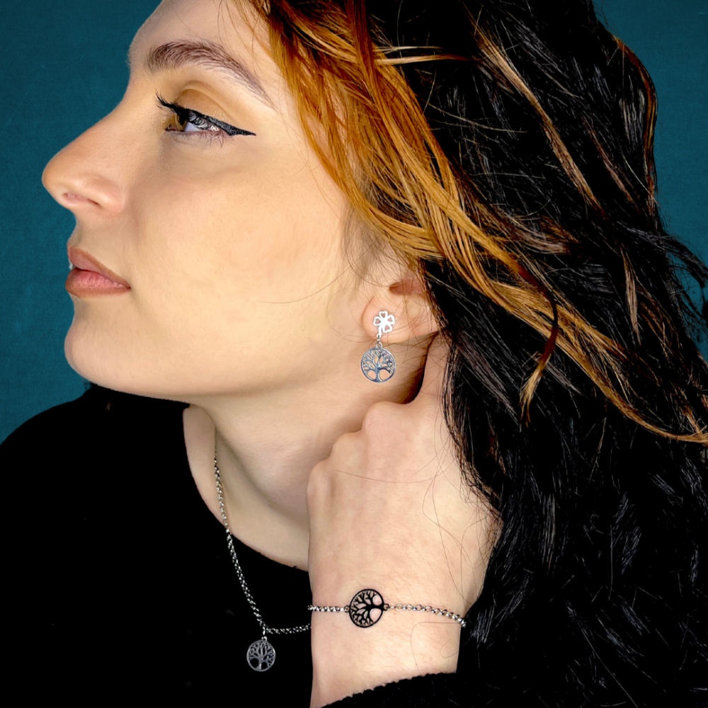 Donna che indossa orecchini pendenti albero della vita con quadrifoglio in metallo argentato