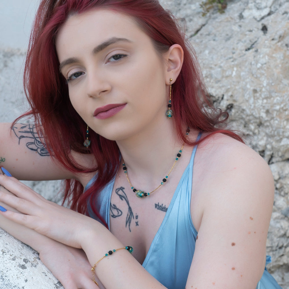 Modella indossa set di gioielli di ungioielloperte.com con bracciale, collana e orecchini con pietra lavica, vetro di Murano e cristalli Swarovski